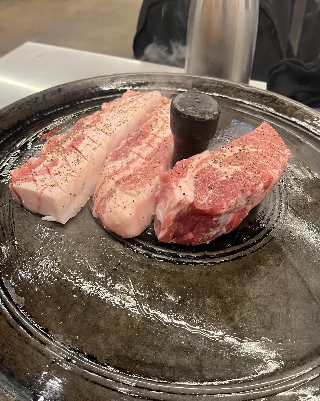 윤기가 흐르는 솥뚜껑 위에서 익어가는 삼겹살