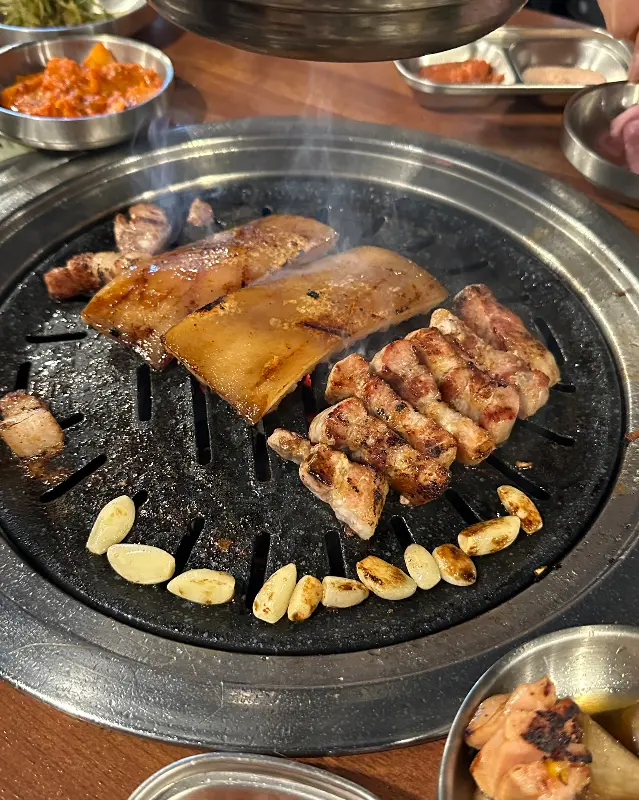 불판 위에서 익어가는 삼겹살과 마늘