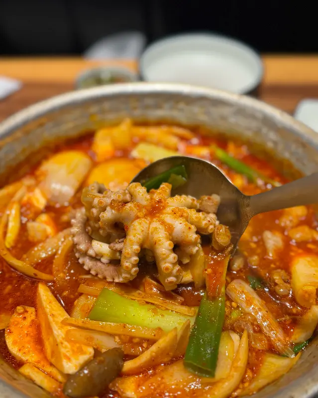 숟가락으로 낙지, 닭고기, 감자를 함께 떠먹는 모습