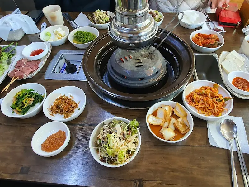 숯불 화로와 테이블 가득 차려진 밑반찬