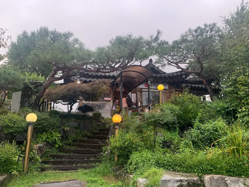 푸른 나무들에 둘러싸인 한옥 식당의 외관