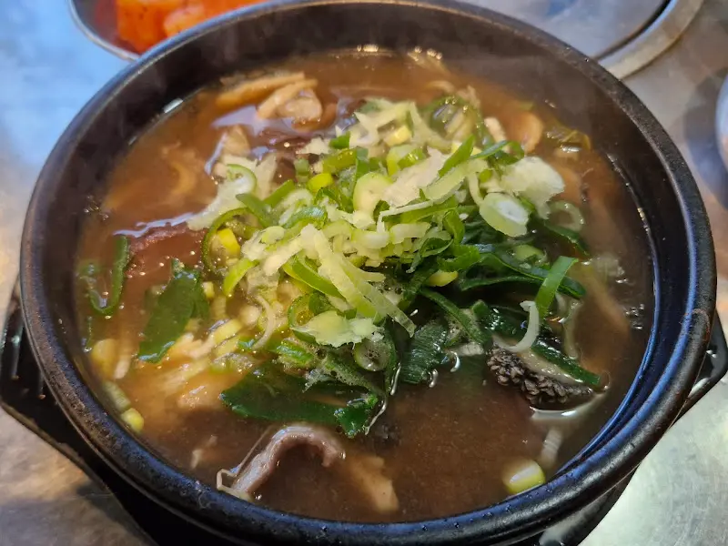 해장국이 담긴 검은 뚝배기 위로 송송 썰린 파가 듬뿍 올려져 있다.