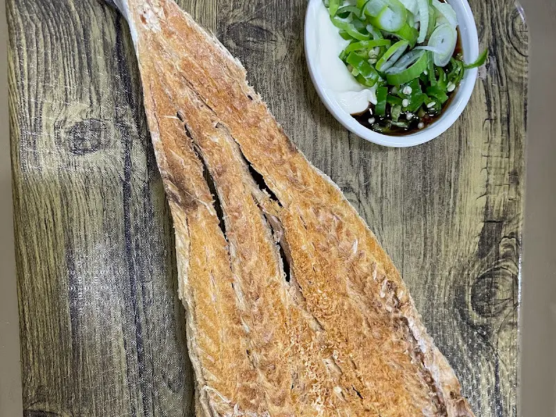 황태 한 마리가 나무 쟁반 위에 놓여 있고, 옆에는 두 종류의 소스가 있다.