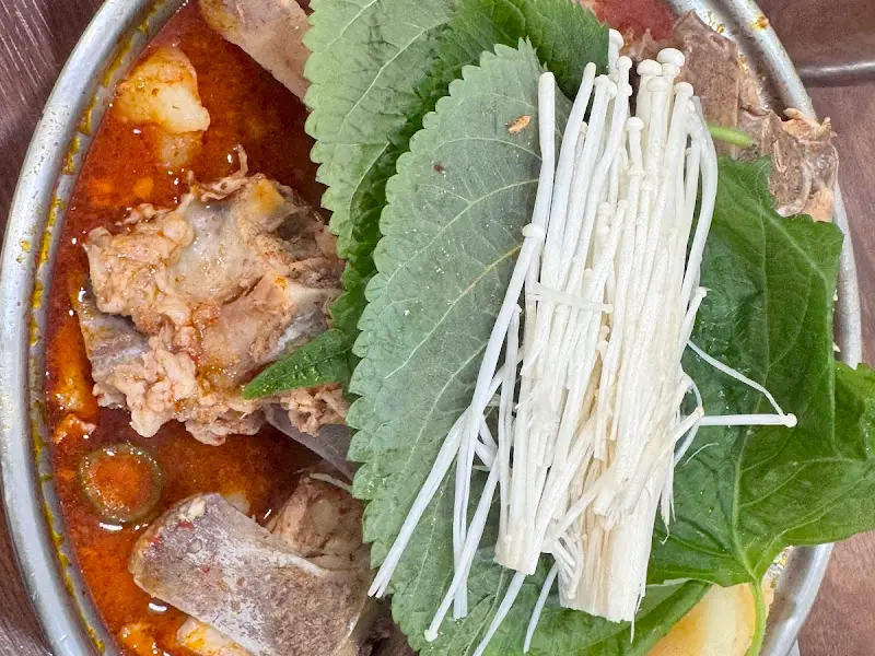 감자탕 냄비 안에는 뼈다귀, 깻잎, 팽이버섯이 가득 담겨 있다.