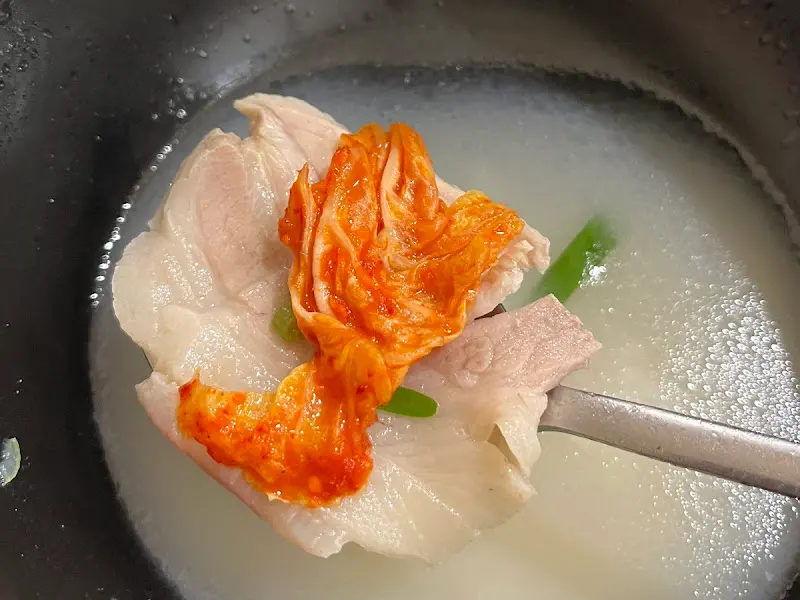 돼지국밥 위에 김치를 올려 먹음직스럽게 찍은 사진