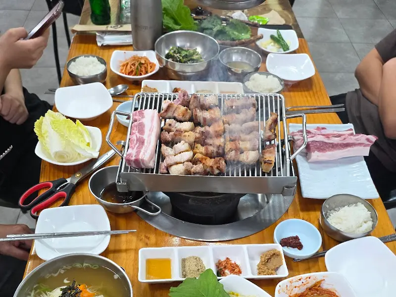 숯불 위에 구워지는 삼겹살과 풍성한 밑반찬