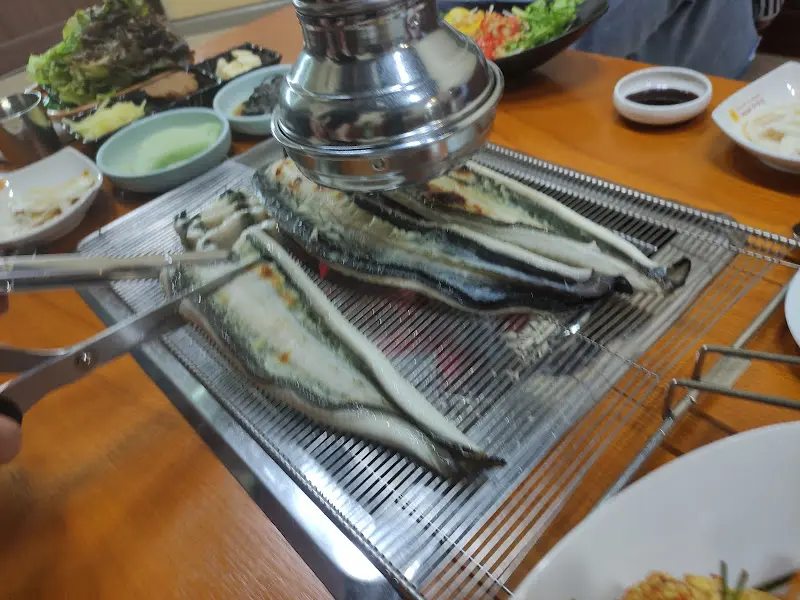 숯불 위에서 익어가는 장어를 먹기 좋게 잘라주는 모습