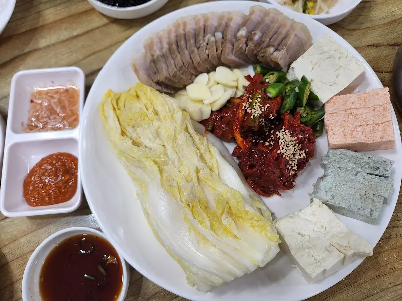 보쌈, 김치, 두부, 마늘이 놓인 접시