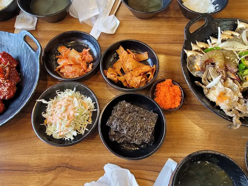 테이블 위에 간장게장, 양념게장, 김치, 김, 밥 등 다양한 반찬들이 놓여 있는 모습