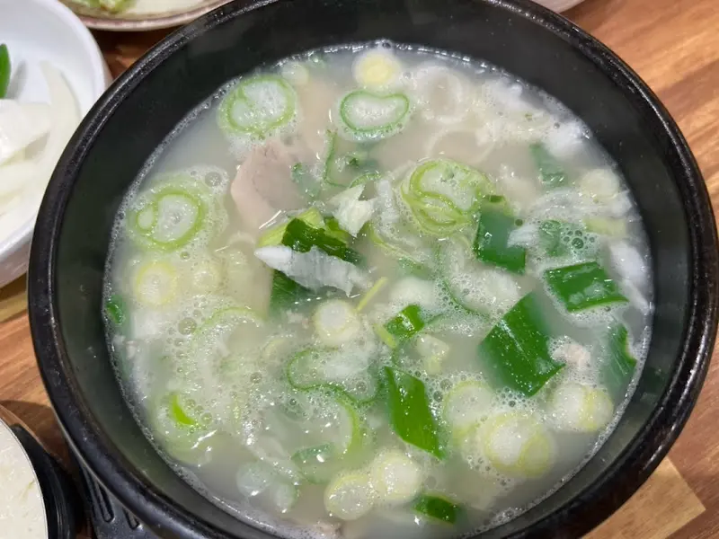 뽀얀 돼지국밥 국물에 파가 듬뿍 올려져 있다.