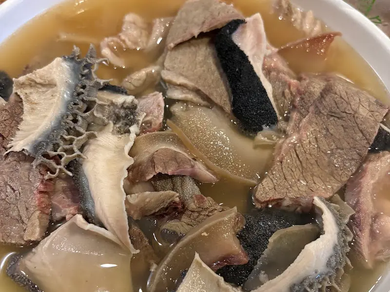 모듬 수육 крупным планом с различными частями мяса, плавающими в бульоне.