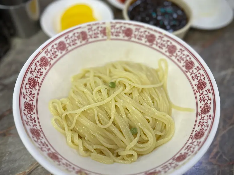 뽀얀 면발 위에 윤기가 흐르는 유니짜장 소스가 듬뿍 올려진 모습