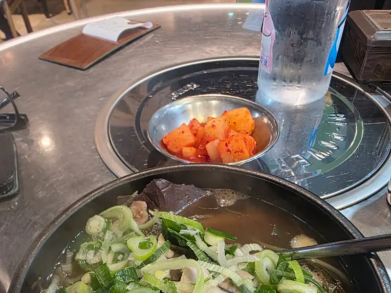 테이블 위에 놓인 해장국 뚝배기와 깍두기가 담긴 작은 그릇