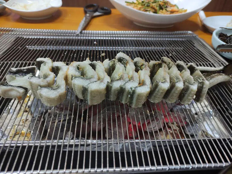 숯불 위에서 먹기 좋은 크기로 잘린 장어들이 줄지어 구워지는 모습