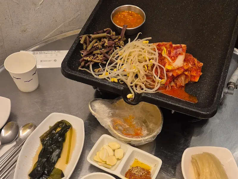 불판 위에 김치, 콩나물, 고사리, 냉삼이 함께 구워지고 있는 모습