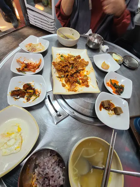 테이블 중앙에 메인 요리가 놓여 있고, 주변으로 다양한 반찬들이 둘러싸고 있다.