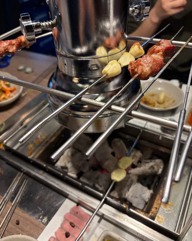 숯불 위에서 구워지는 양꼬치와 마늘 꼬치의 모습