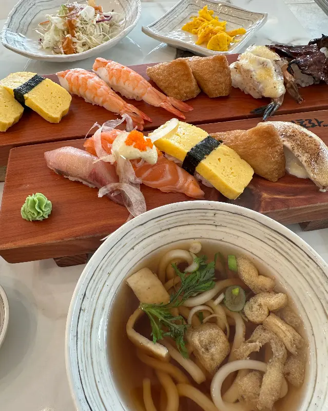 다양한 종류의 초밥과 우동이 함께 놓여 있는 테이블