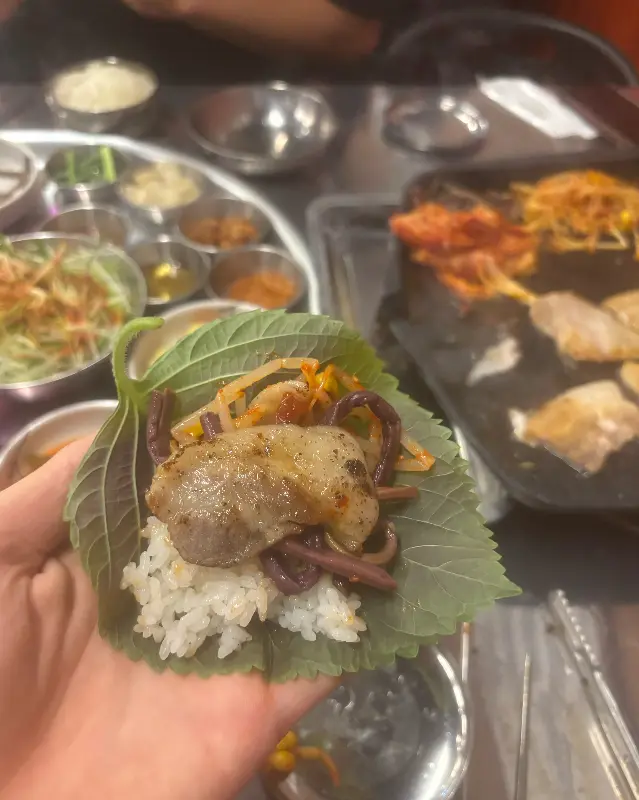 깻잎에 쌈을 싸서 먹는 모습