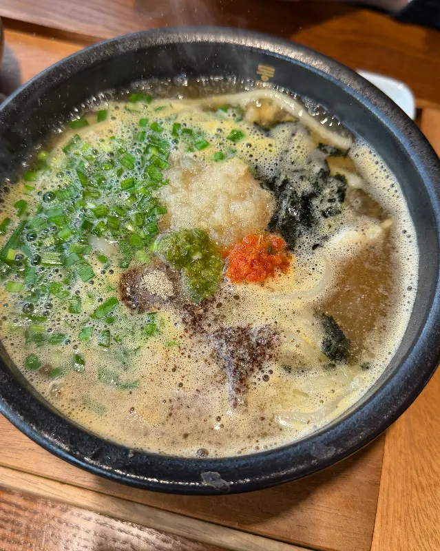 고명과 함께 보글보글 끓고 있는 우동 돼지국밥