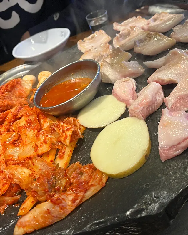 돌판 위에 구워지는 고기와 김치, 감자