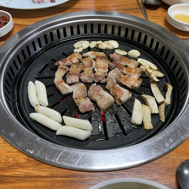 불판 위에서 구워지고 있는 돼지고기와 떡, 버섯