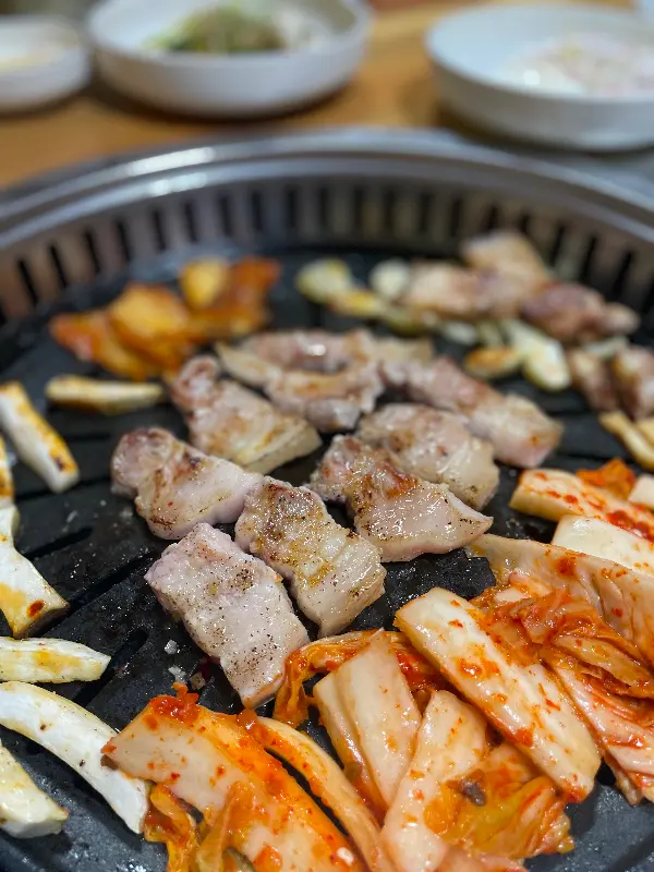 잘 구워진 돼지고기와 김치가 불판 위에 놓여 있는 모습