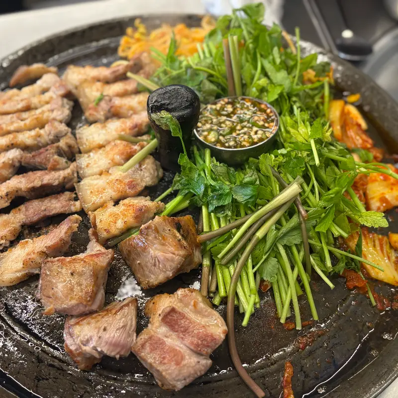 솥뚜껑 위에 삼겹살, 목살, 미나리, 김치의 환상적인 조합