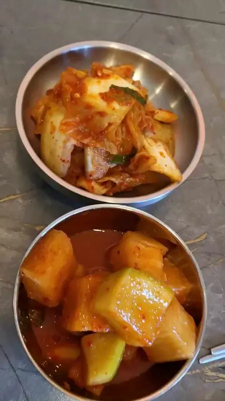 잘 익은 김치와 깍두기가 담긴 작은 스테인리스 그릇