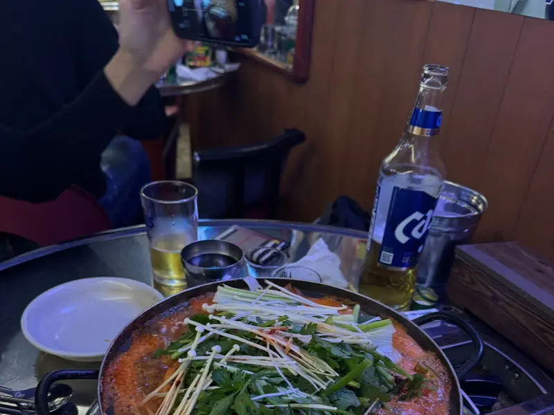 푸짐하게 담긴 알탕과 밑반찬, 그리고 시원한 맥주 한 잔이 놓인 테이블 풍경