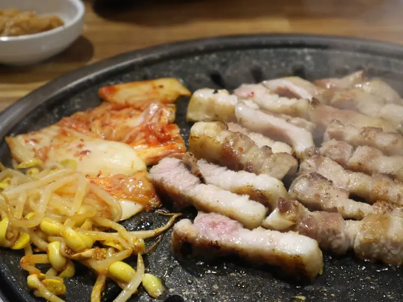 불판 위에서 익어가는 뒷고기, 김치, 콩나물