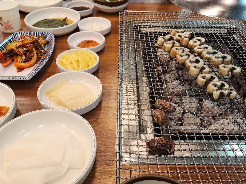 숯불 위에서 구워지는 장어와 다양한 밑반찬