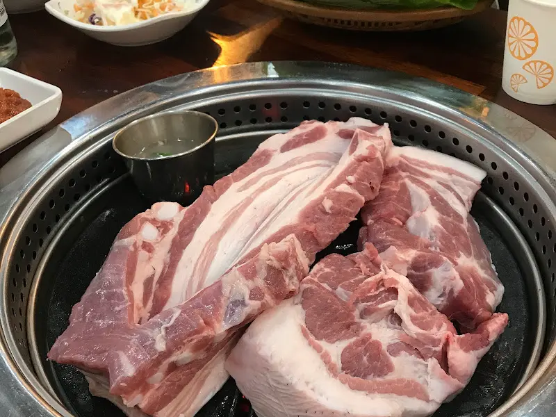 두툼한 오겹살이 불판 위에 올려져 있는 모습