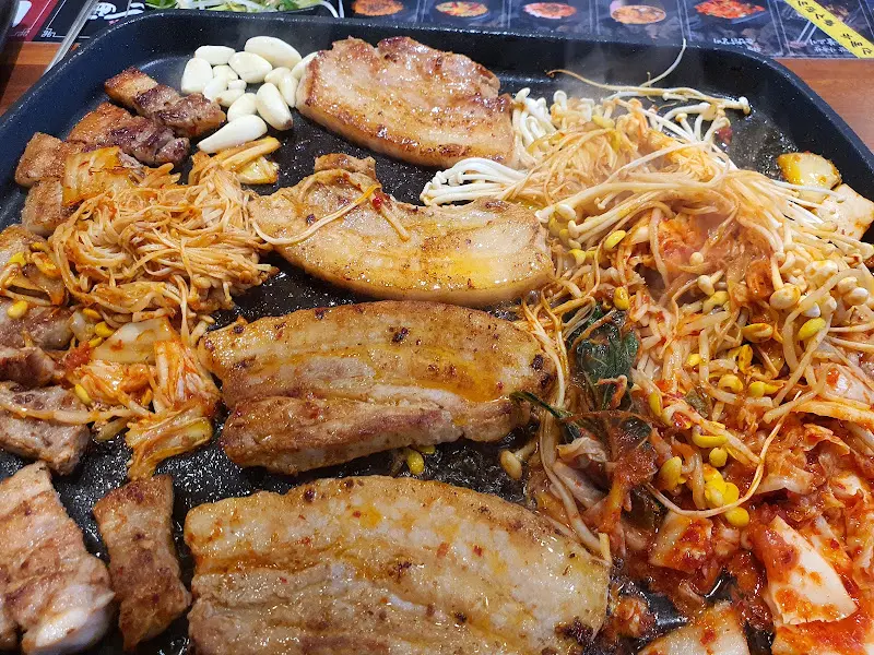 불판 가득 구워진 삼겹살과 김치, 버섯