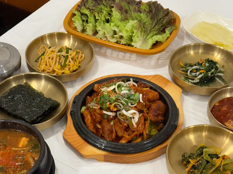 놋그릇에 담긴 정갈한 반찬들과 제육볶음, 풍성한 쌈채소