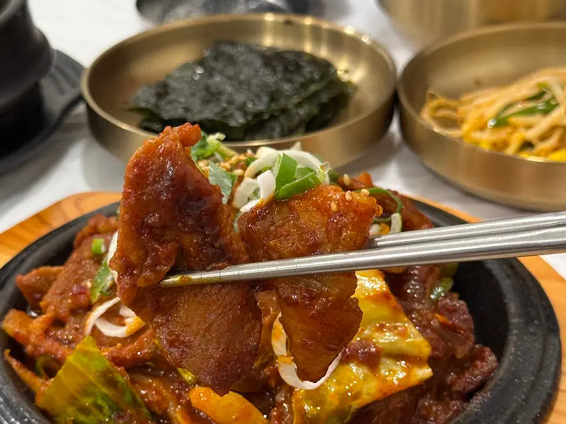 젓가락으로 집어올린 윤기가 흐르는 제육볶음