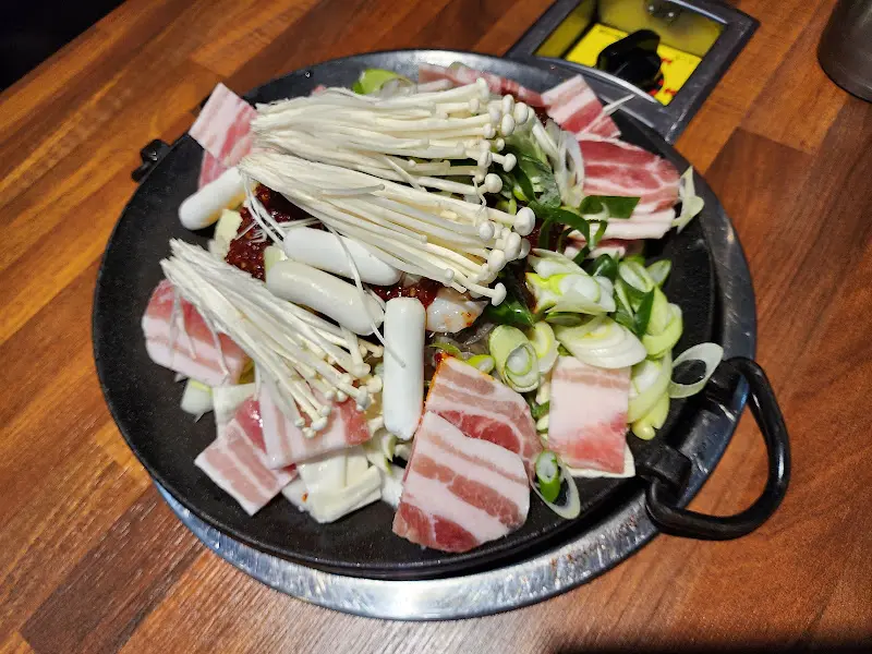 삼겹살, 쭈꾸미, 떡, 버섯 등이 푸짐하게 담긴 철판 요리