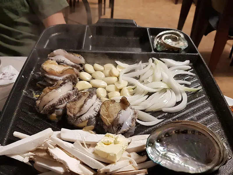 불판 위에 올려진 전복, 마늘, 양파