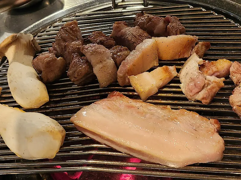 불판 위에서 맛있게 익어가는 삼겹살과 버섯