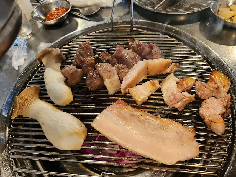 불판 위에 올려진 삼겹살과 버섯