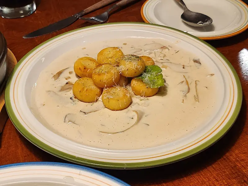 크림 소스에 담겨 있는 뇨끼 위에 치즈 가루가 뿌려져 있는 모습