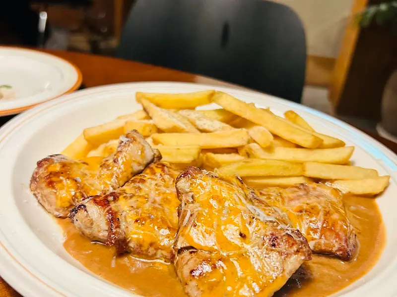 스테이크 위에 소스가 뿌려져 있고 옆에 감자튀김이 놓여 있는 모습