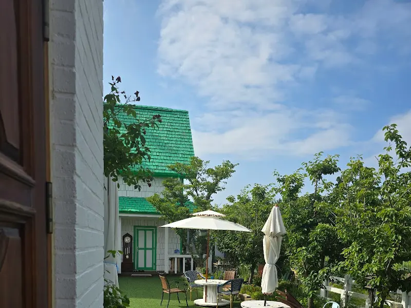 앤트리 카페의 야외 공간. 초록색 지붕 집과 테이블이 조화롭게 어우러져 있다.