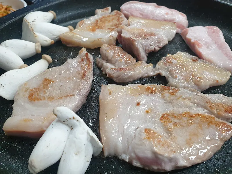 불판 위에 구워지는 앞다리살과 고사리, 묵은지, 콩나물