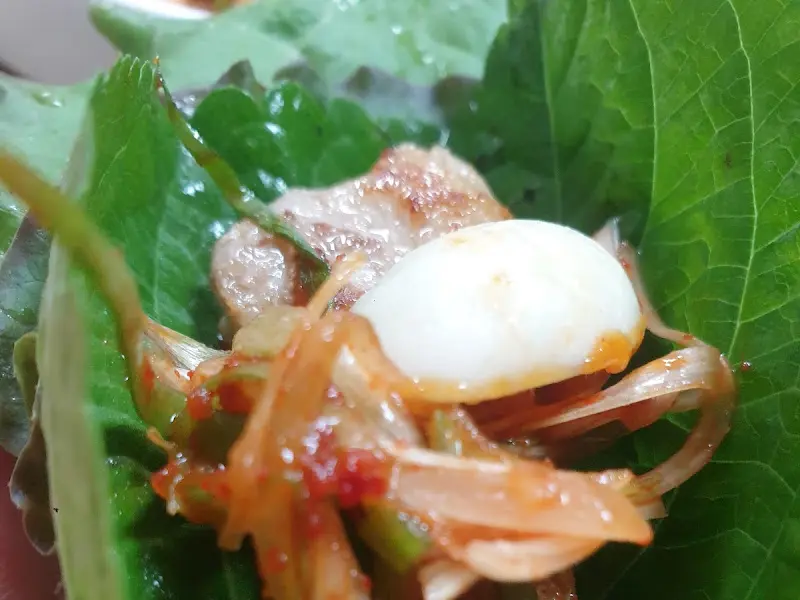 쌈 채소에 싸여진 돼지고기와 양념된 채소