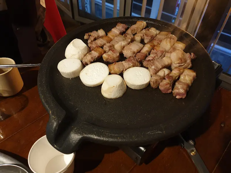 불판 위에서 구워지는 삼겹살과 버섯