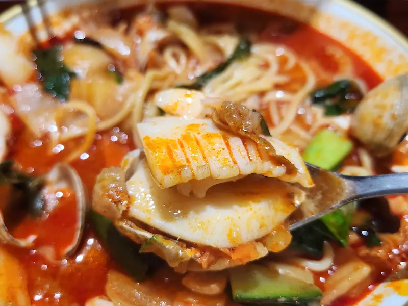 갑오징어가 듬뿍 들어간 짬뽕을 숟가락으로 들어올린 모습