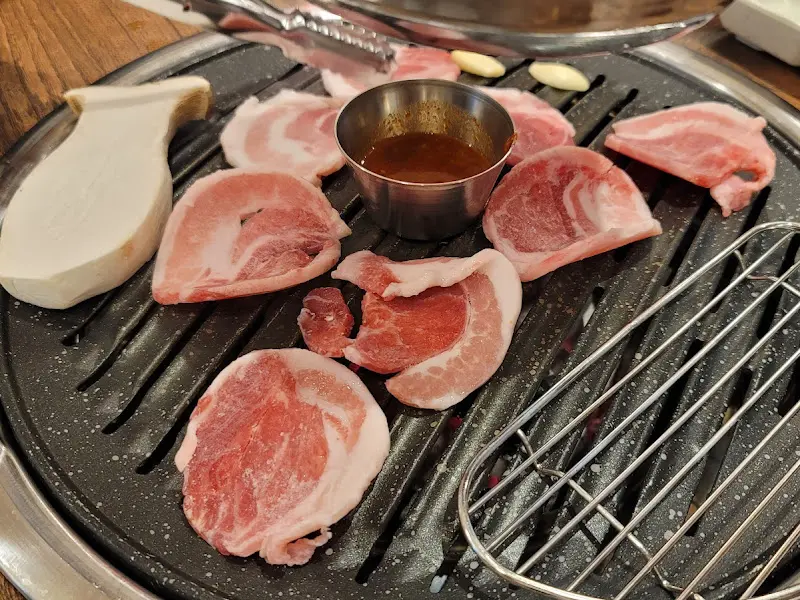 불판 위에 돼지고기를 올리고 굽는 모습, 윤기가 자르르 흐른다.