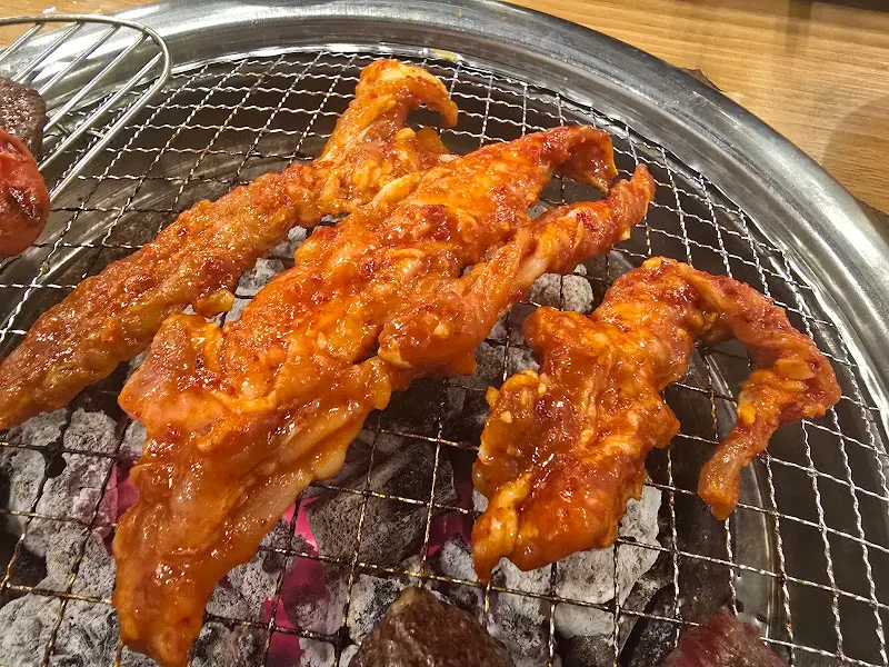 숯불 위에서 노릇하게 익어가는 매콤 닭목살구이