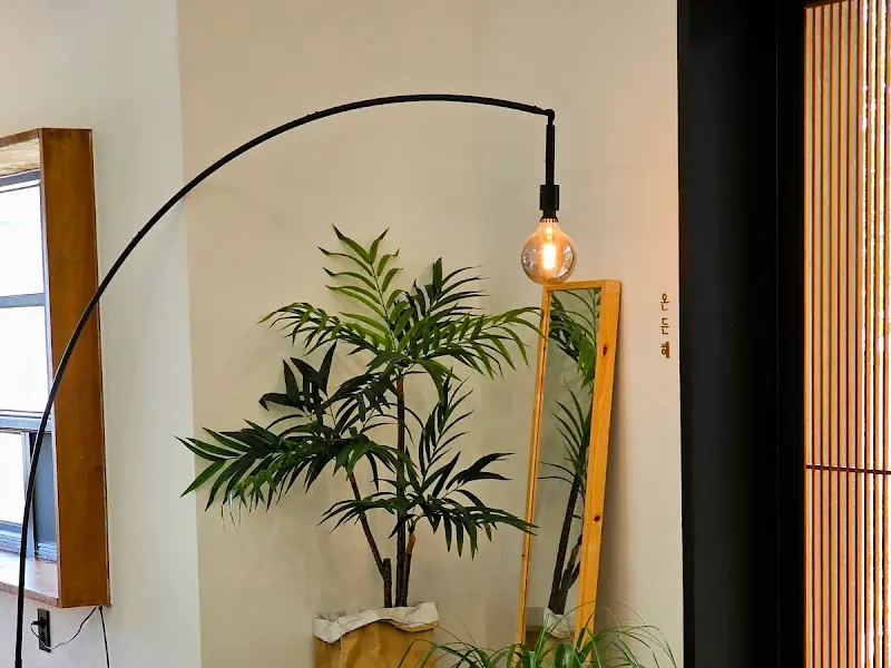 카페 내부에 놓인 플로어 램프와 푸른 식물이 조화롭게 어우러져 있다.